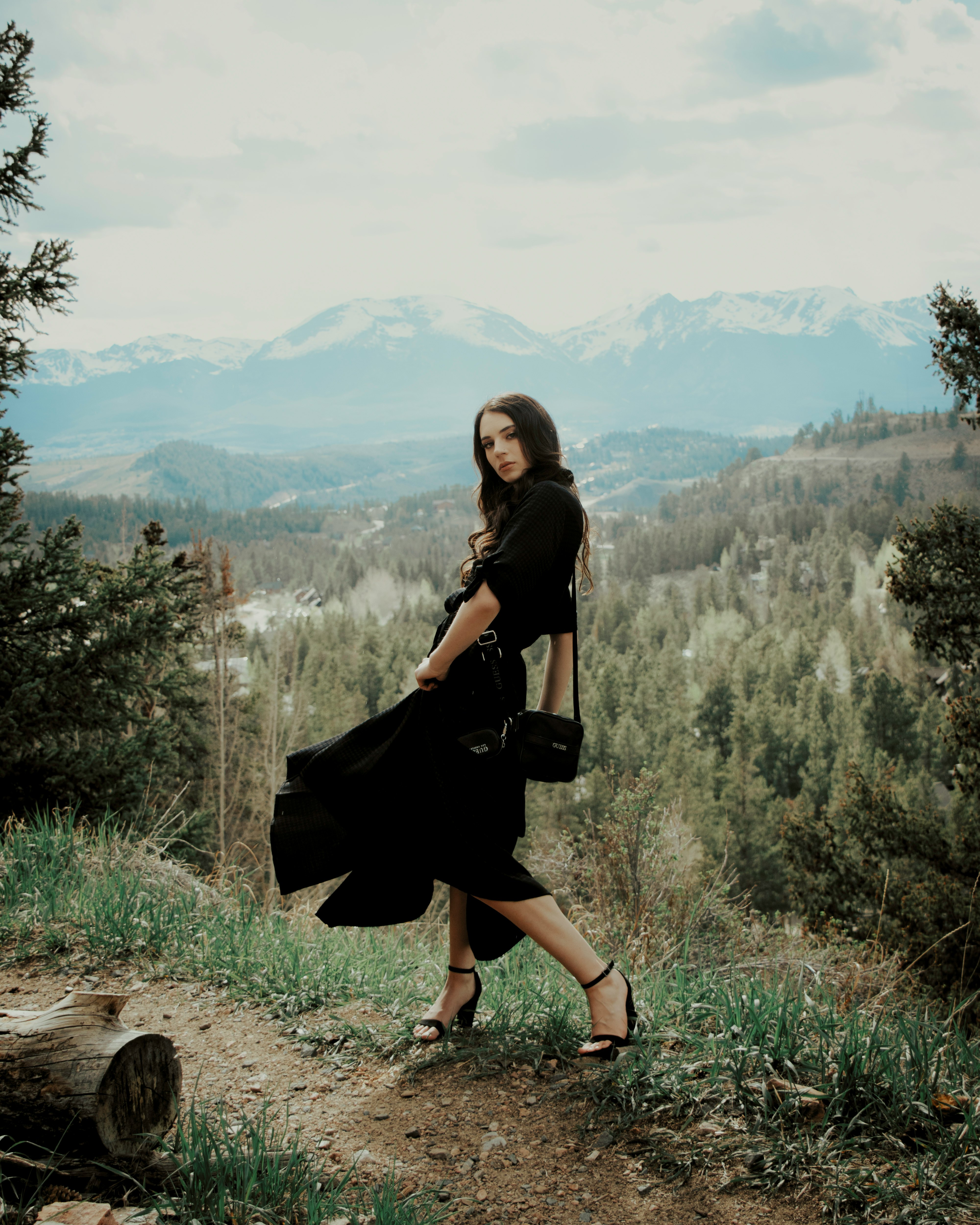 woman in black dress sitting on brown rock during daytime
